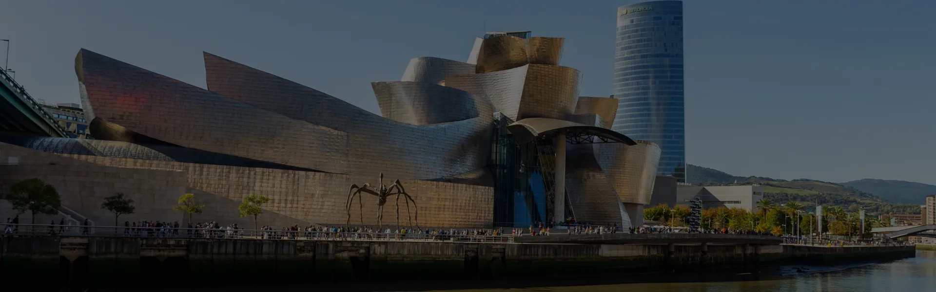 Imponente vista del Museo Guggenheim en Bilbao, una obra arquitectónica de vanguardia con su característico diseño curvo y su revestimiento metálico. En el exterior, la escultura de la araña 'Maman' y el paseo junto a la ría de Bilbao ofrecen un ambiente vibrante y cultural. Explora nuevas experiencias con la privacidad y discreción de un sex shop en Bilbao, donde el placer y la innovación se fusionan en un espacio exclusivo.